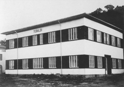 Vista ravvicinata del Padiglione Tebaldi nel 1963, con la scritta ancora visibile sulla facciata. L’architettura razionale, tipica del periodo, evidenzia linee semplici e finestre con inferriate.